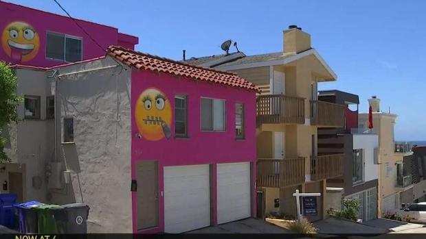 woman paints giant emojis on house